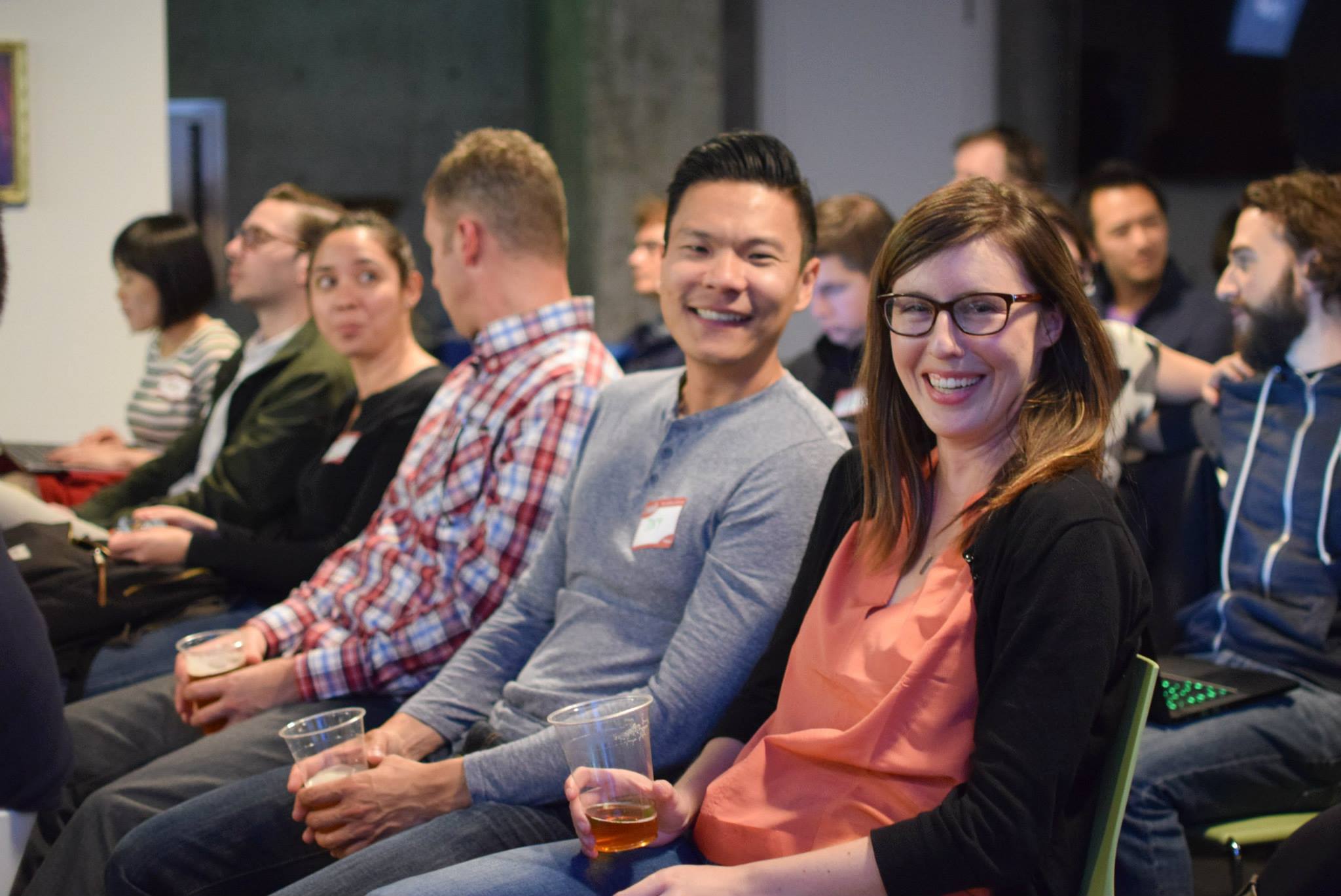 Attendees smiling in the front row of a UXNight talk