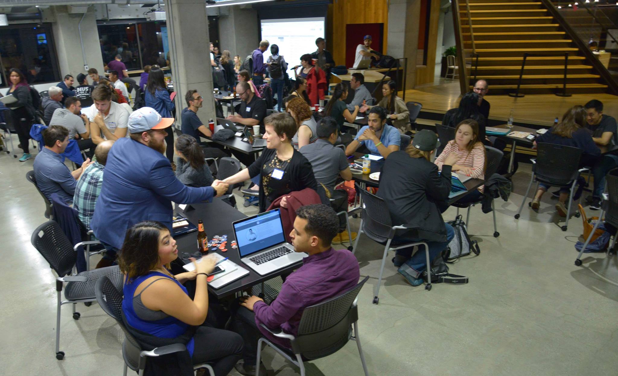 A packed Mentor Night in an open coworking space, with designers meeting across dozens of tables