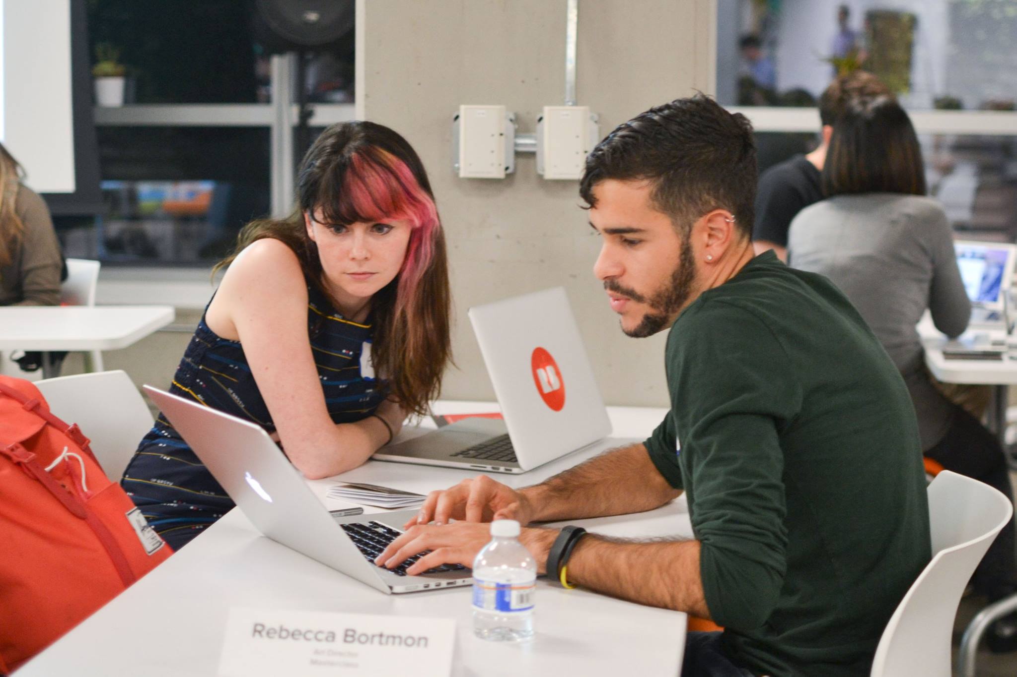 A mentor and mentee reviewing work together on laptops at a Mentor Night table